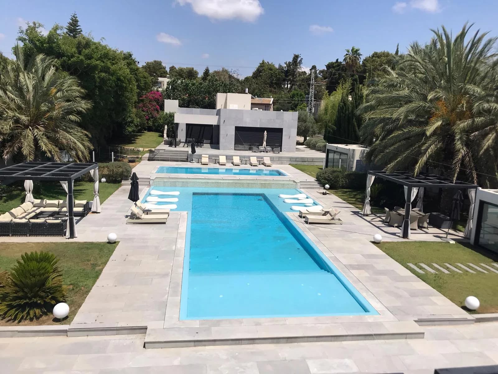 Luxury villa with a long swimming pool, stone terraces and palm gardens